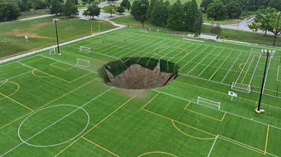 Sink hole in the middle of a green football pitch.