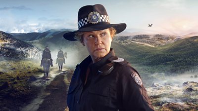 composite image of Leah Purcell as a police officer looking offscreen. background of grass terrain and mountains and two police officers on horses walking away from camera