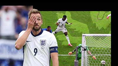 England player Harry Kane holding his hand on his face, with a goal being scored in the background