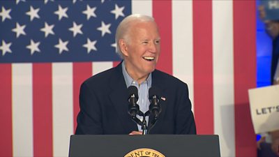 Biden smiles in front of the United States flag