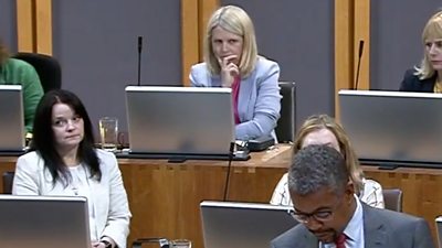 Hannah Blythyn sat in the back of the Senedd chambers with Vaughan Gething at the front