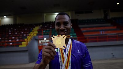 Anu holding a medal in a sports hall