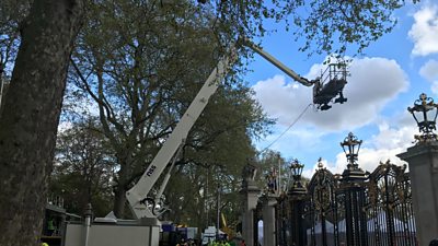 Two cameras mounted on a large cherry picker outside Buckingham Palace