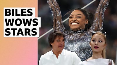 Simone Biles with her hands in the air and a huge smile