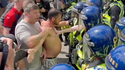 Police officers holding back topless protester