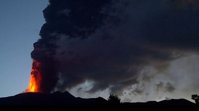 Volcano spewing lava and smoke at dawn