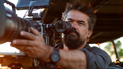 Close up of man looking through lens of large camera