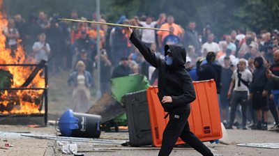 A protestor dressed in black throwing an object
