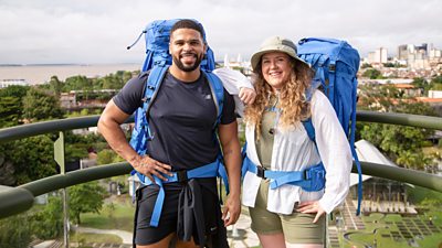 Kola Bokinni and his cousin Mary Ellen stand on a balcony wearing backpacks