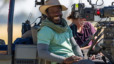 man in a truck sitting behind a camera smiling