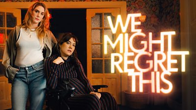 Key Art. Characters Jo (Elena Saurel) and Freya (Kyla Harris) look to camera from a living room. Glowing text beside them reads: “We Might Regret This.”