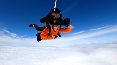 Lloyd skydiving in blue skies. He is in an harness with an instructor