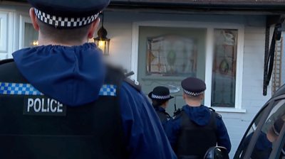 Police officers in uniform standing in front of a door