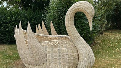 Giant willow sculpture of a swan in a grassy field