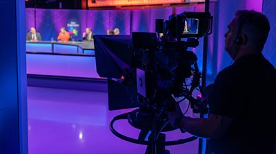 Behind the scenes photo of camera operator and live panel in TV studio