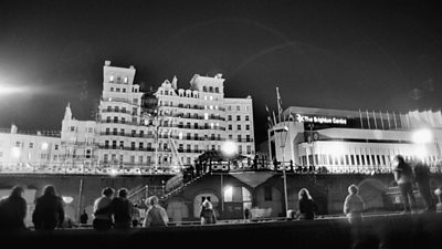 a black and white image of the grand hotel in brighton after the bombing with people looking in the foreground