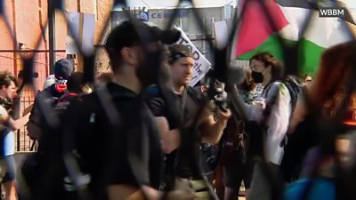 A group of people with one carrying a Palestinian flag are seen through fencing