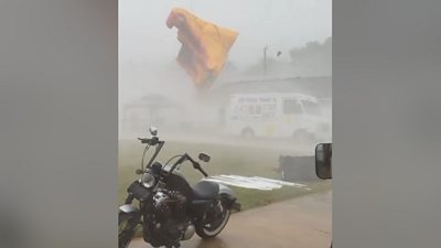 A bouncy castle flies into the air above a van and motorbike