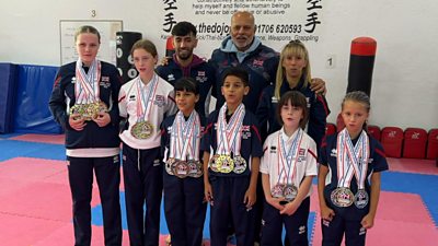 Karate students in Rochdale pose together with tutors after winning more than 100 medals