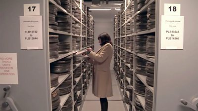 Woman looking through shelves of film in an archive