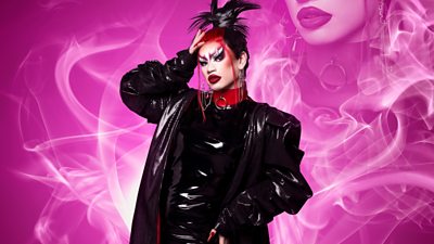 Drag Queen Actavia wearing all leather with a red choker and red and black hair with pink smoke surrounding her