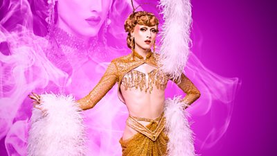 Drag Queen Marmalade wearing a gold jewelled bra and underwear with gold fabric on the bottom and a gold top that's just sleeves. She's got white fur on her cuffs and on a headpiece with gold jewellery. Pink smoke effect in the background with a partial image of Marmalade in it