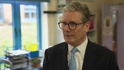 Keir Starmer wearing a suit, speaking in a classroom