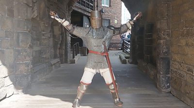 James Lovatt, aka Sir Runs a Lot, dressed in medieval chainmail and full helm, doing star jumps