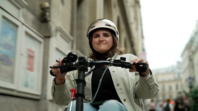 A lady in a shiny helmet rides a disability scooter on a Paris street