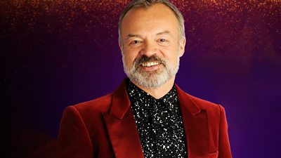 Graham Norton wears a sparkling black shirt under a red velvet jacket