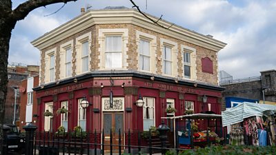 A shot of the EastEnders set shows The Queen Victoria pub on Albert Square, with market stalls on the street beside the pub