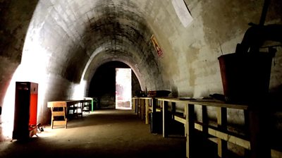 Inside a bunker with arched white stone walls and wooden fixtures.