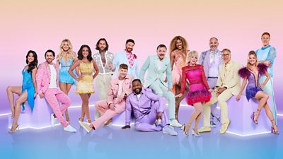 The Strictly Come Dancing 2024 celebrities sit and stand around a series of purple boxes lit with bright lights. They all wear colourful suits and dresses in pastel shades and hot pinks.