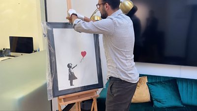 Man with gloves on setting painting on easel