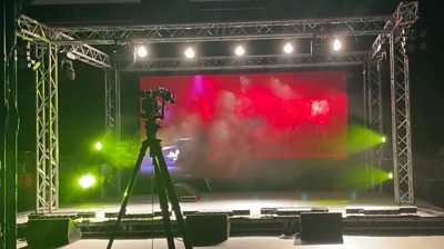 An image of lighting and smoke effects on an empty stage - a locked off camera is pointing at the empty stage.