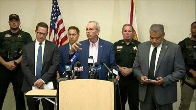 Palm Beach County Sheriff Ric Bradshaw at a podium with several other men around him