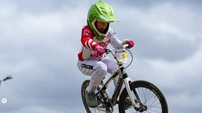 Boy in white tracksuit jumping on BMX bike