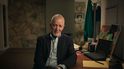 Bill Misenhimer leaning on a desk with a laptop looking to camera