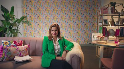 Kate Andersen Brower sitting on a pink sofa with her arm leaning on it and she's smiling to camera