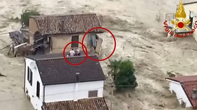 Building falls apart, as people shelter on roof