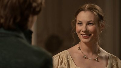 A woman smiles as she talks to another person on the edge of the image. They both wear period clothing from the Georgian Era.