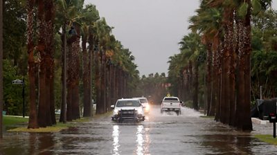 Vehicles drive along a flooded street in Pete Beach, Florida