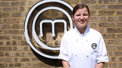 contestant Chloe standing in front of MasterChef M smiling for the camera and wearing a MasterChef branded shirt