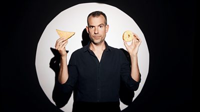 Chris van Tulleken holding a dougnut and a sandwich