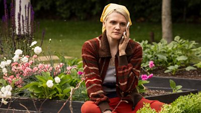 Jo (Gayle Rankin) on her phone sitting amongst flower beds