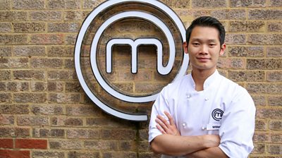 Man wearing MasterChef branded t-shirt in front of MasterChef logo looking at camera