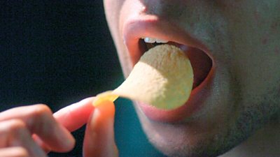 Close up of a person putting a crisp in their mouth