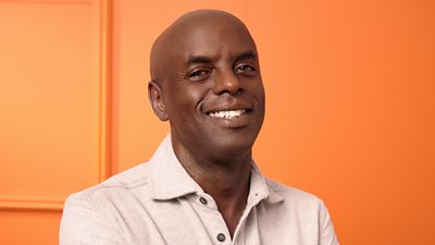 A head shoulders shot of Trevor Nelson, set against and orange background