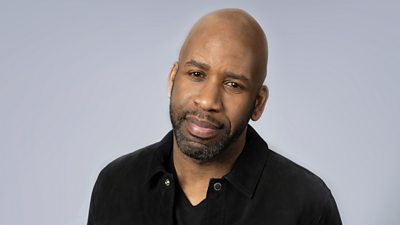 DJ Spoony wears a black shirt and is pictured against a grey background