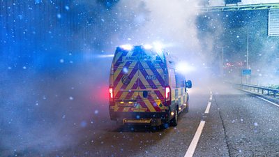 An ambulance drives down a large road into cold fog and snow